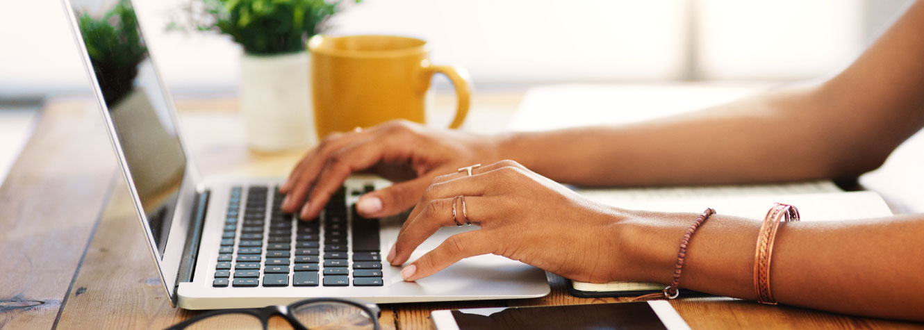 Close up of a person's hands using a laptop.